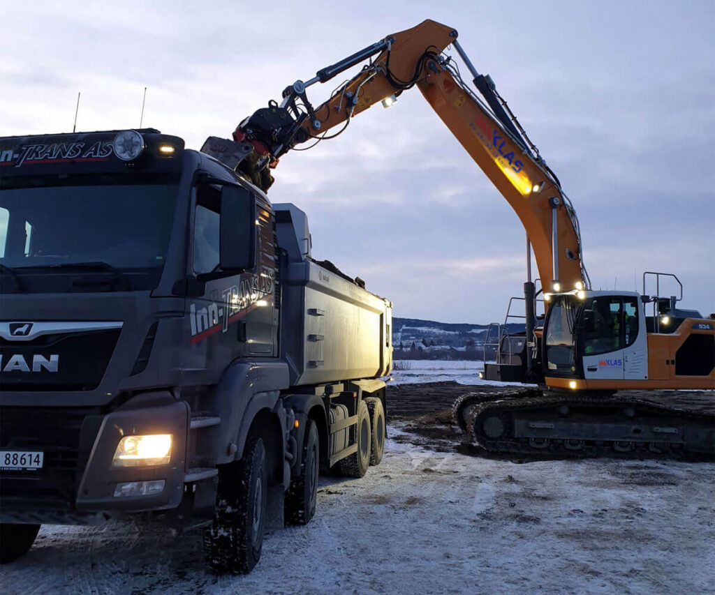 Gravemaskin og lastebil på oppdrag.